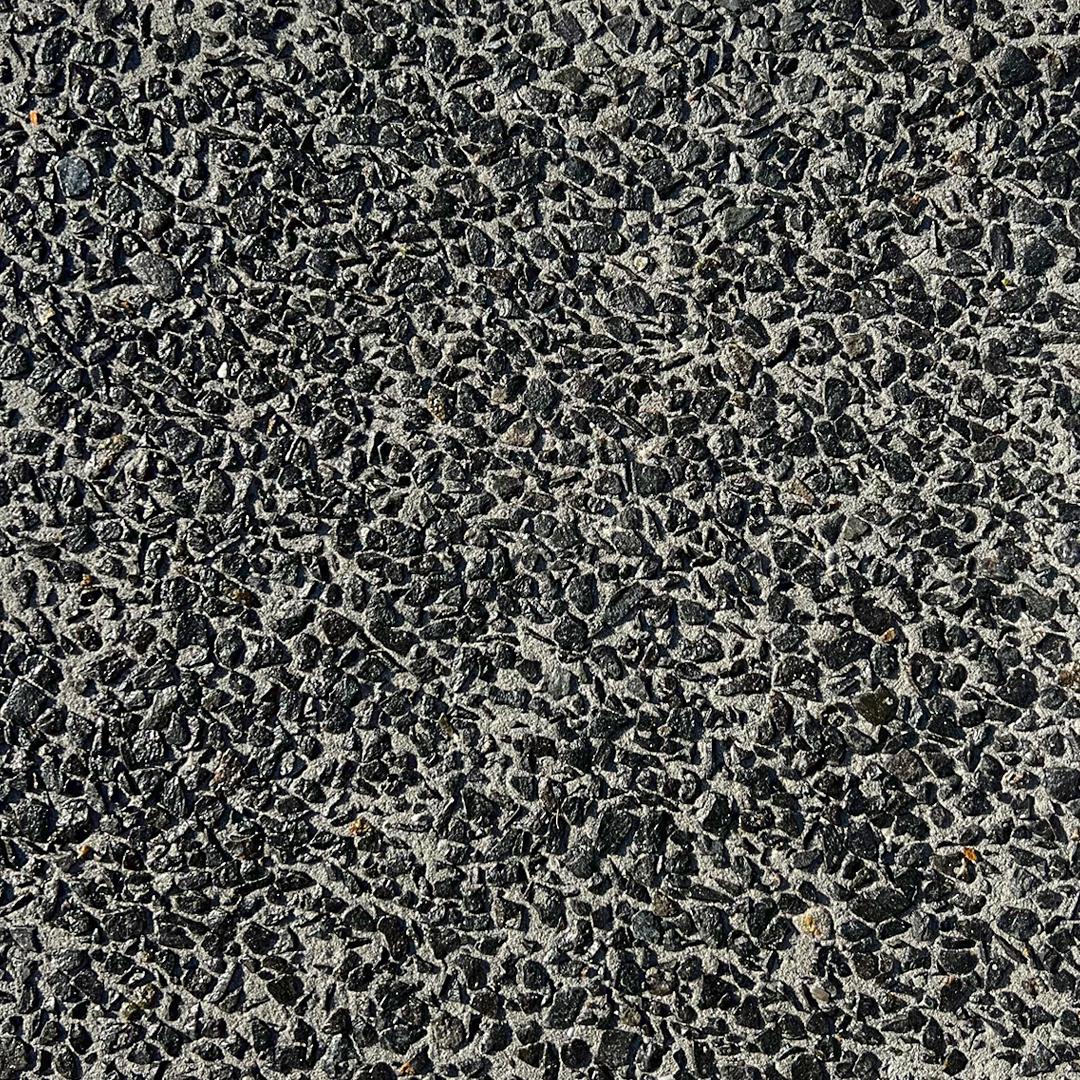 Close up swatch of exposed aggregate concrete in the shade Midnight