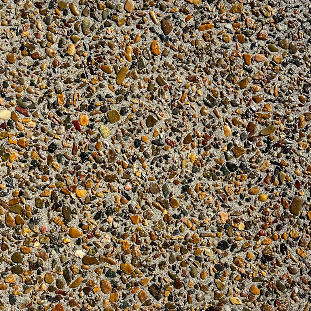 Close up swatch of exposed aggregate concrete in the shade River Red